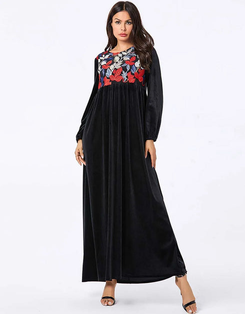A flowing black or emerald green velvet abaya with delicate gold embroidery around the cuffs and neckline