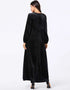 A flowing black or emerald green velvet abaya with delicate gold embroidery around the cuffs and neckline